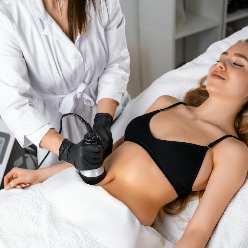 Young woman getting ultrasound cavitation body contouring treatment and anti cellulite therapy